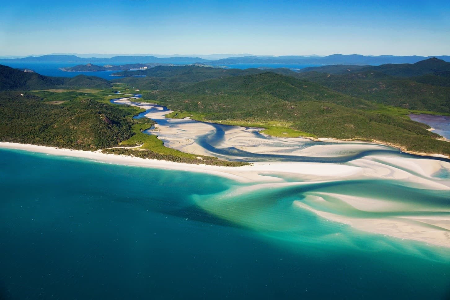 white sandy beach with greenery on the background