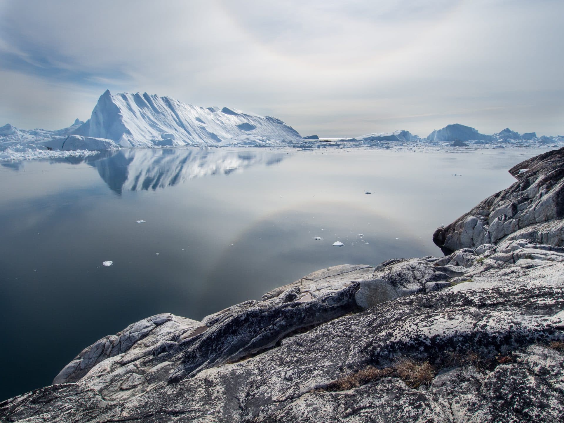 Glacier floating on the horizon. A block of grey rock in the foreground.