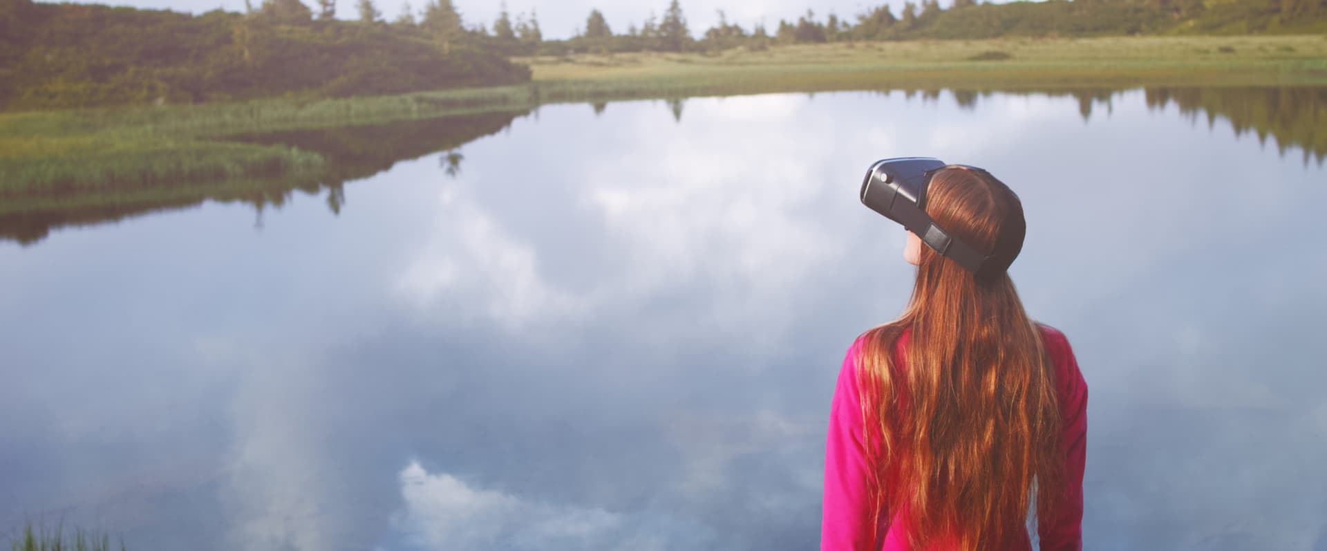 Woman in virtual reality glasses standing near a lake