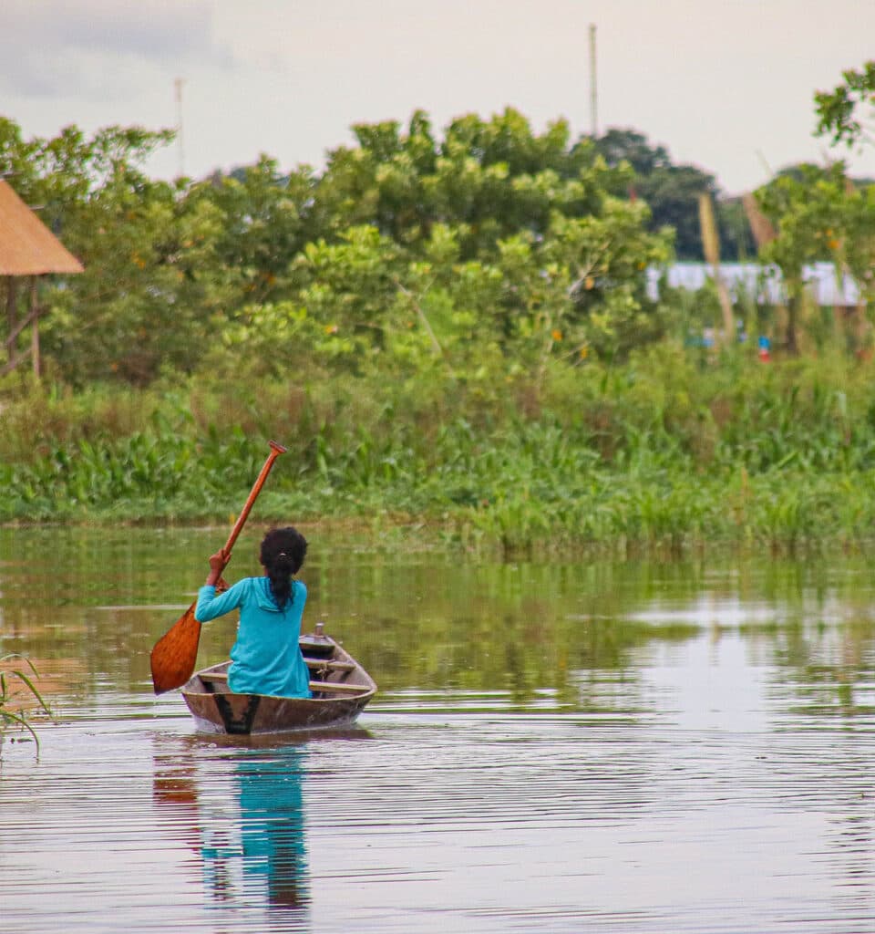Woman paddling canoe on the Amazon River.