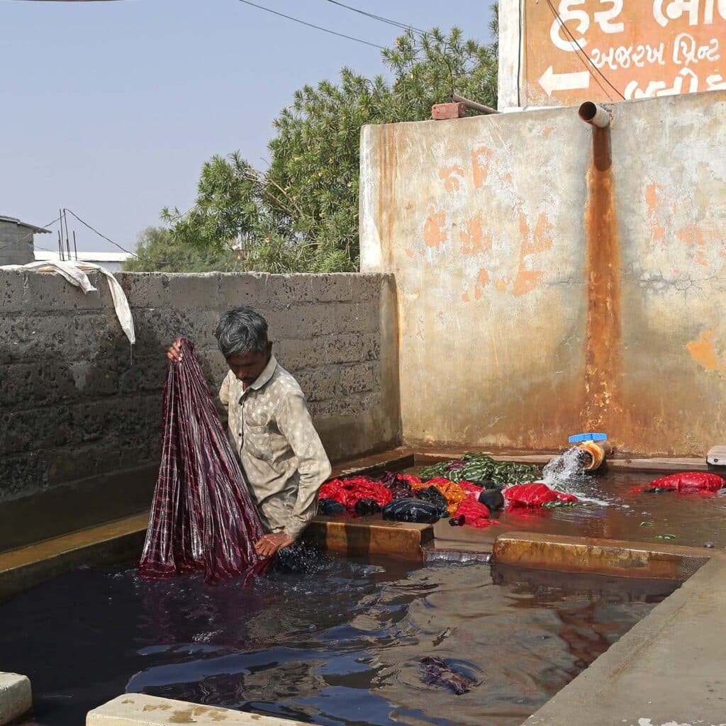 BHUJ, INDIA – JANUARY 5, 2025: Process of tissue staining. Artisanal textile production, work in India. Indian workers paint fabrics by hand in village near Bhuj, Gujarat. Handmade clothes. Hard work