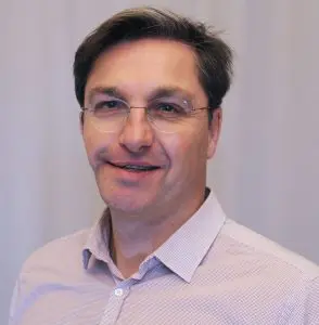 Man smiling with a white shirt and rimless glasses