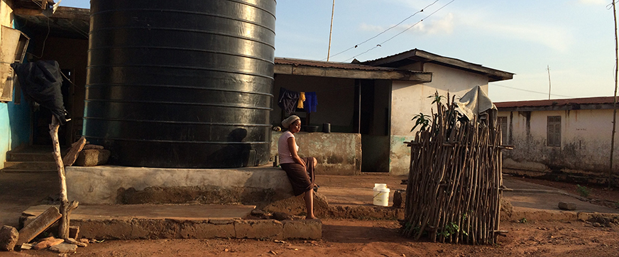 Black woman sitting in front of a water tank