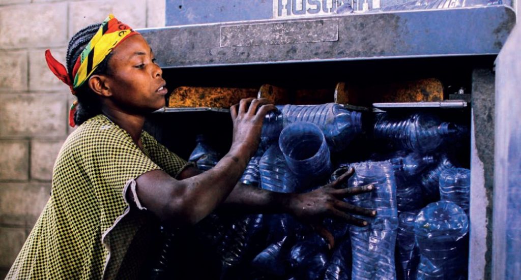 Woman crushes plastic bottles at recycling plant, Hawassa, Ethiopia. Photo: Georgette Mrakadeh-Keane