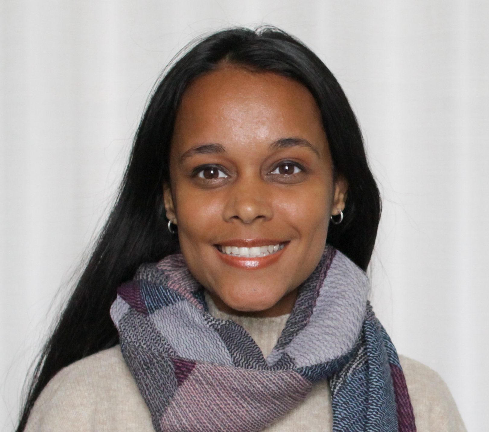 Brown woman with a smile, multicolour scarf over an off white sweater