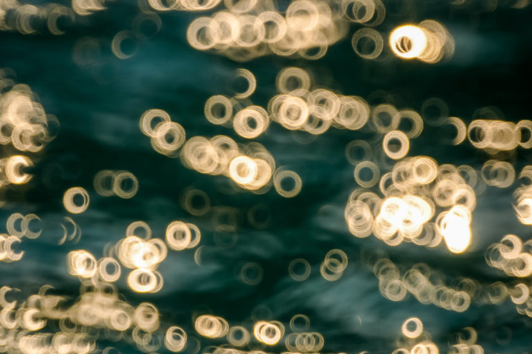 Rendered out-of-focus points of light, reflecting off the surface of the ocean.