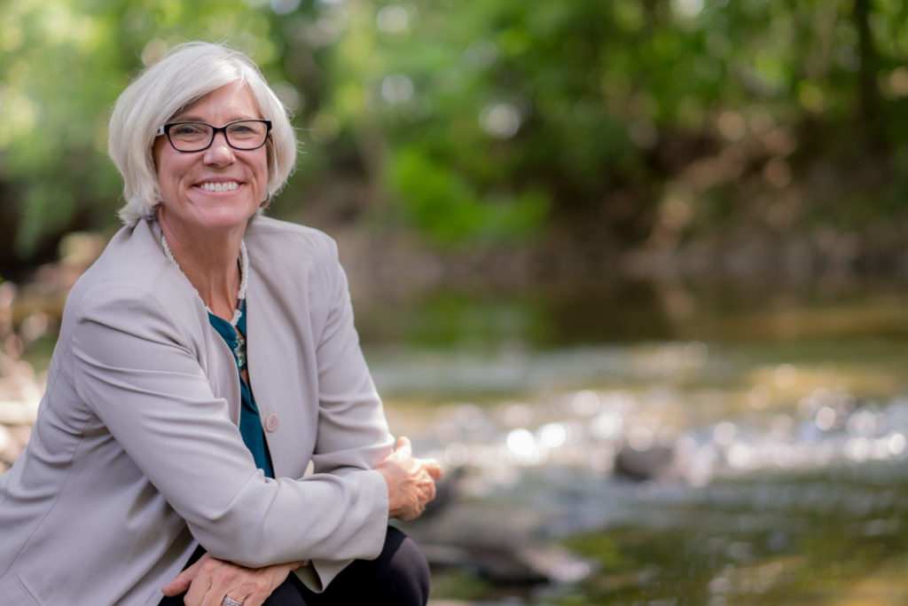 Joan Rose outside, sitting by a river