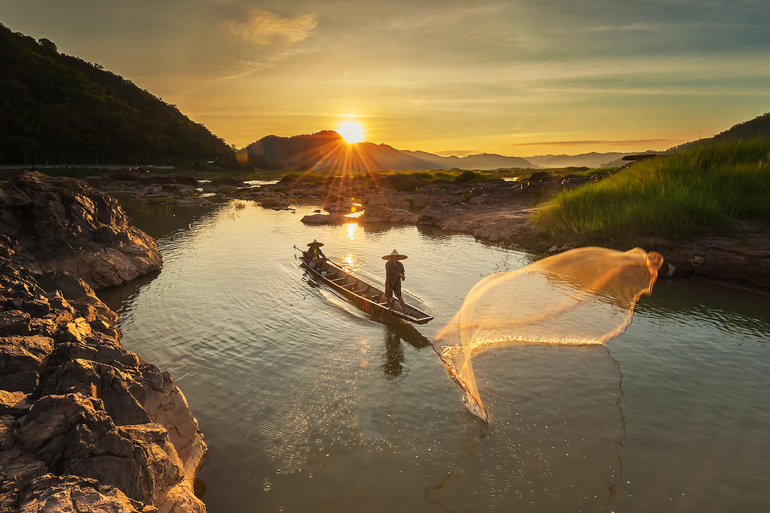 Fisherman throwing his net at sunrise on a tributory of the Mekong river.