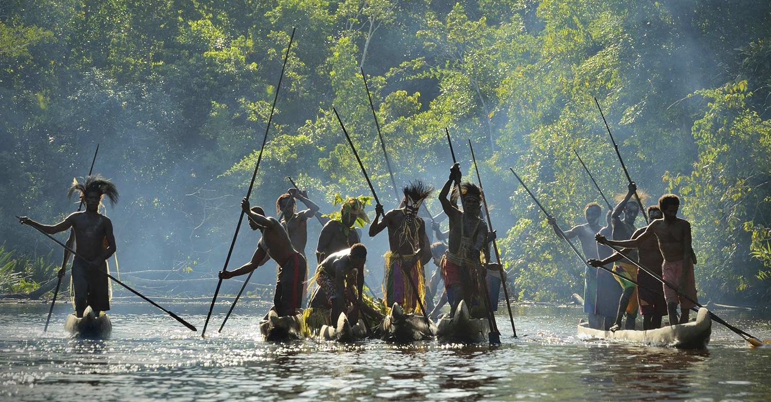 Asmat warriors paddling through the jungle in Papua New Guinea.