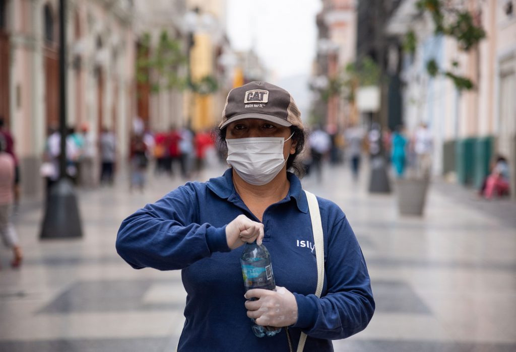 Lima, Peru - May 04, 2020: Woman wearing face masks and opening bottle of water.