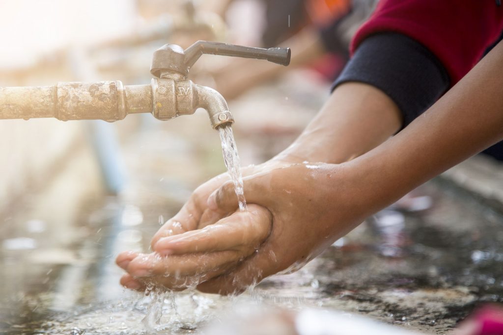 kid washing his hand with tap water