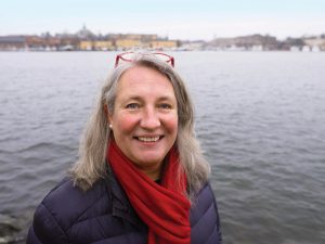 Portrait of Katarina Veem wearing a red scarf with the city of Stockholm as a blurry background