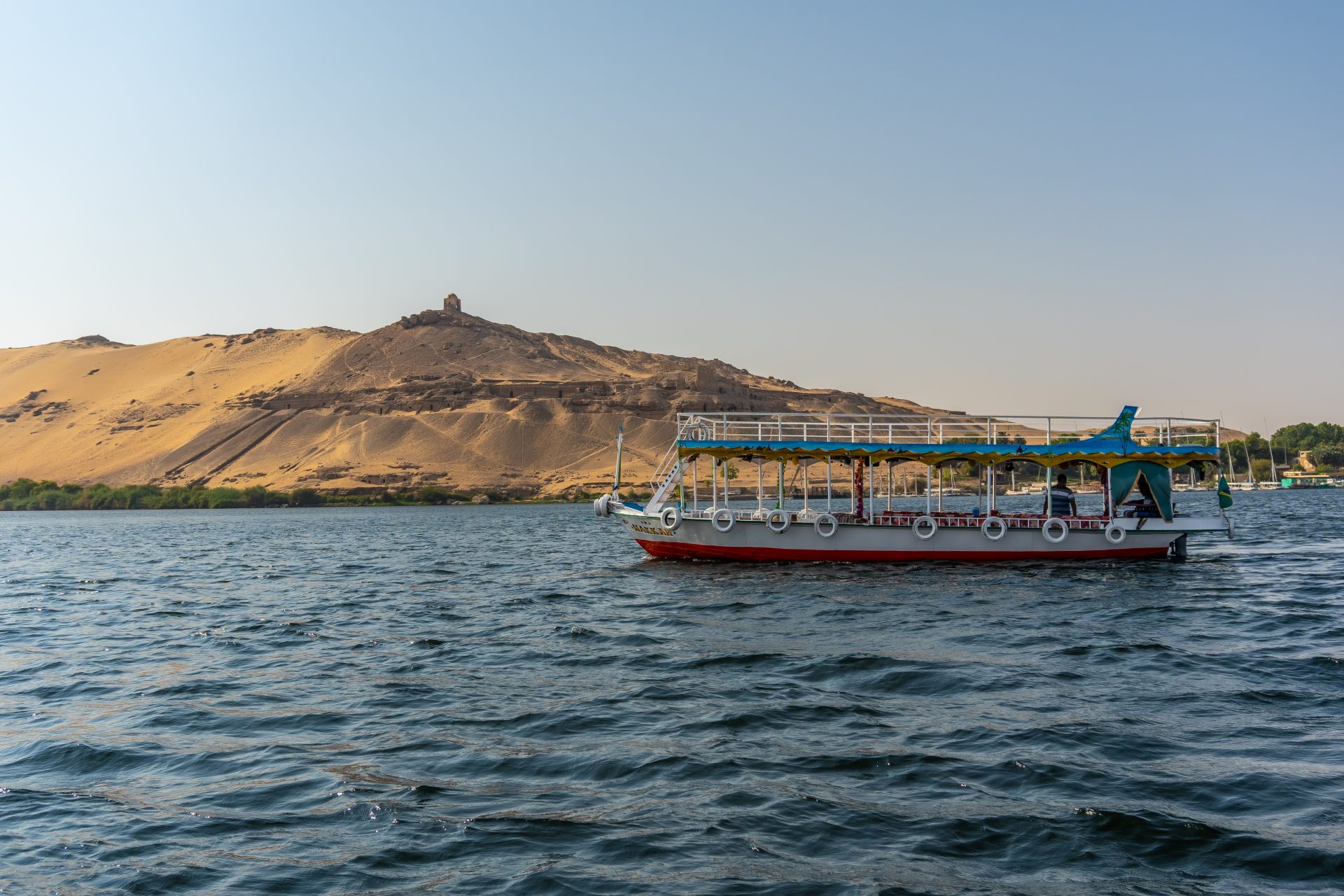 Boat navigating on the Nile river with a sand dune in the background