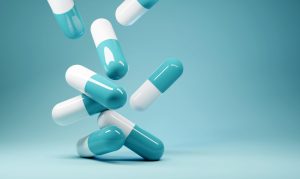 Teal-white pills dropping against a teal background