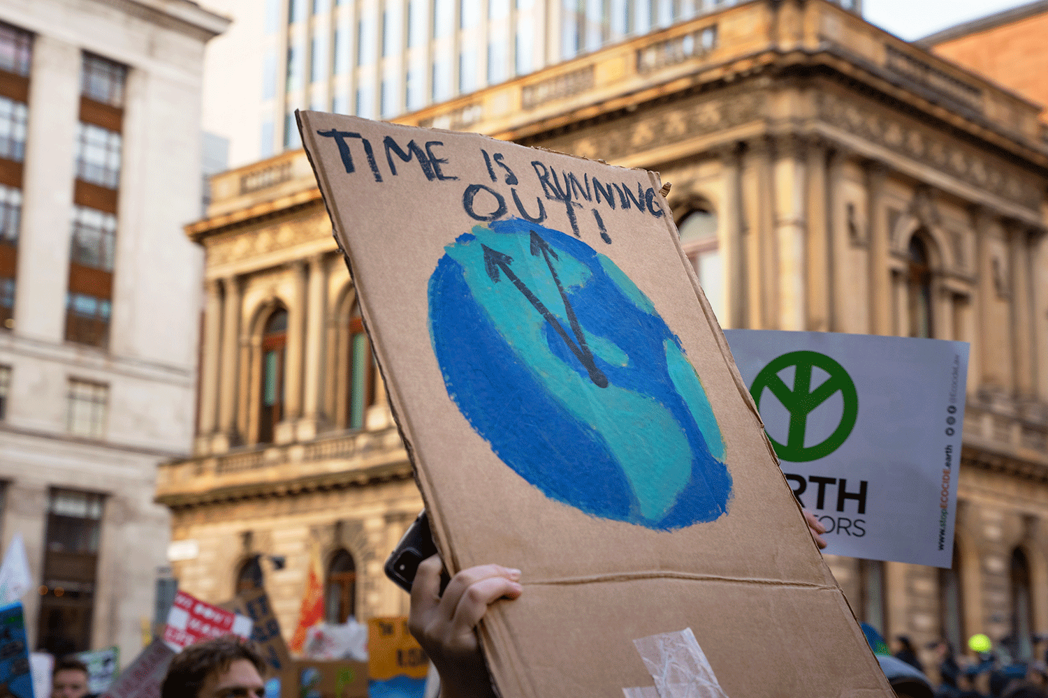 A sign saying 'Time Is Running Out' showing a clock in shape of Earth ticking - at COP26 Youth march