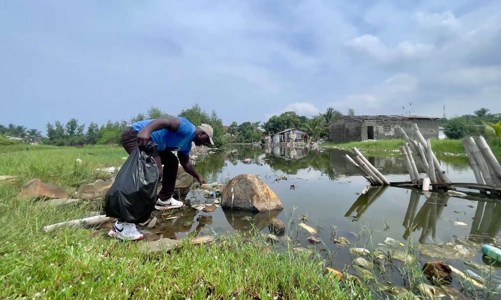 Man wearing a blue shirt, participating in a water cleaning operation in Liberia