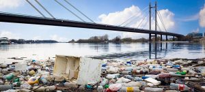 plastic waste floating on water with bridge on the background