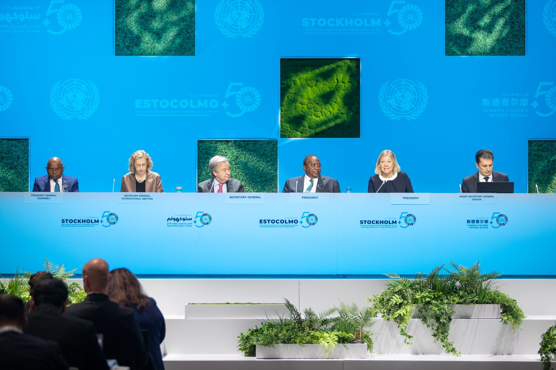 Six people sitting at high table in front of audience with blue background