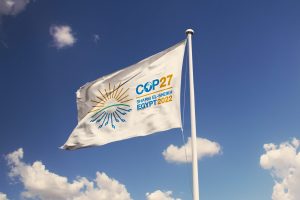 COP 27 logo on a white flag floating on a blue sky with light clouds