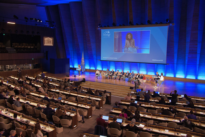 conference room with a presenter, big screen on the stage and audiences sitting theatre style