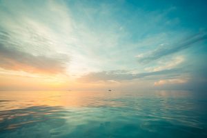 Peaceful seascape with wide horizon of a cloudy sky at sunrise and a turquoise see