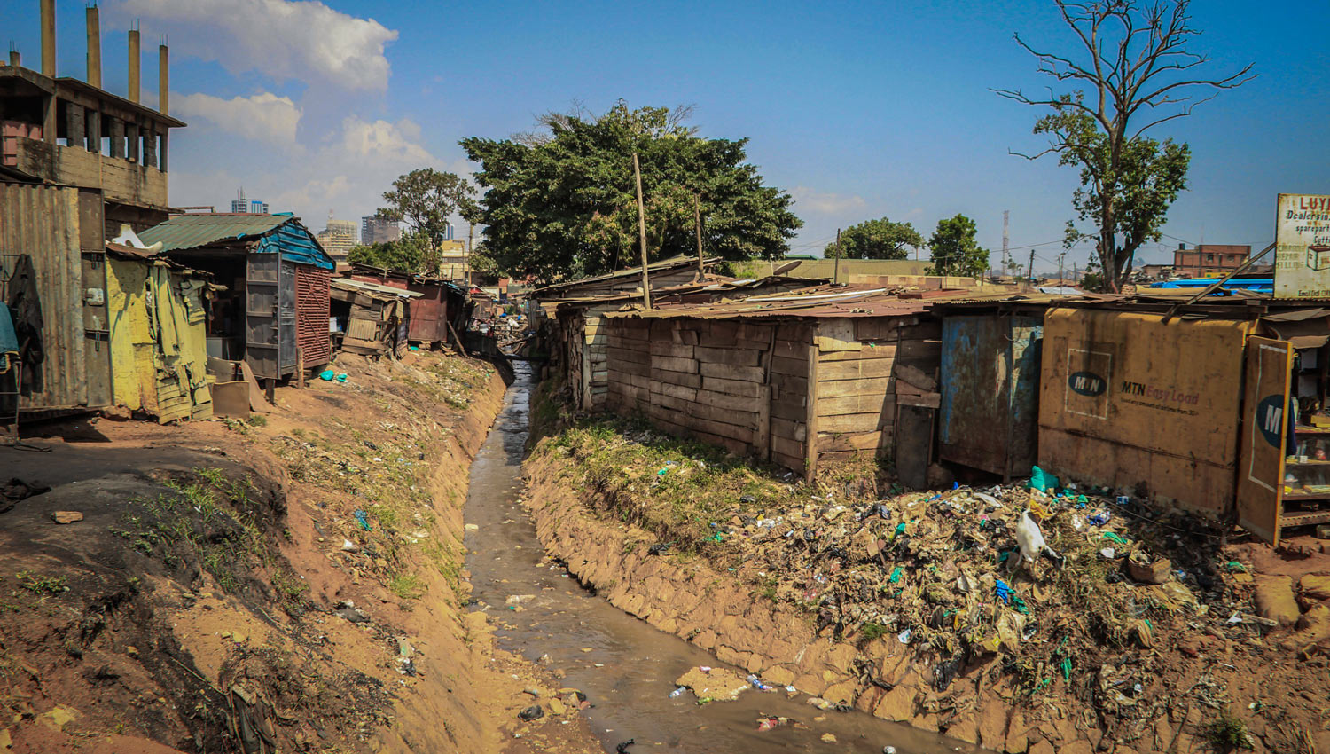 Stream with litter running between makeshift shacks in an African slum.