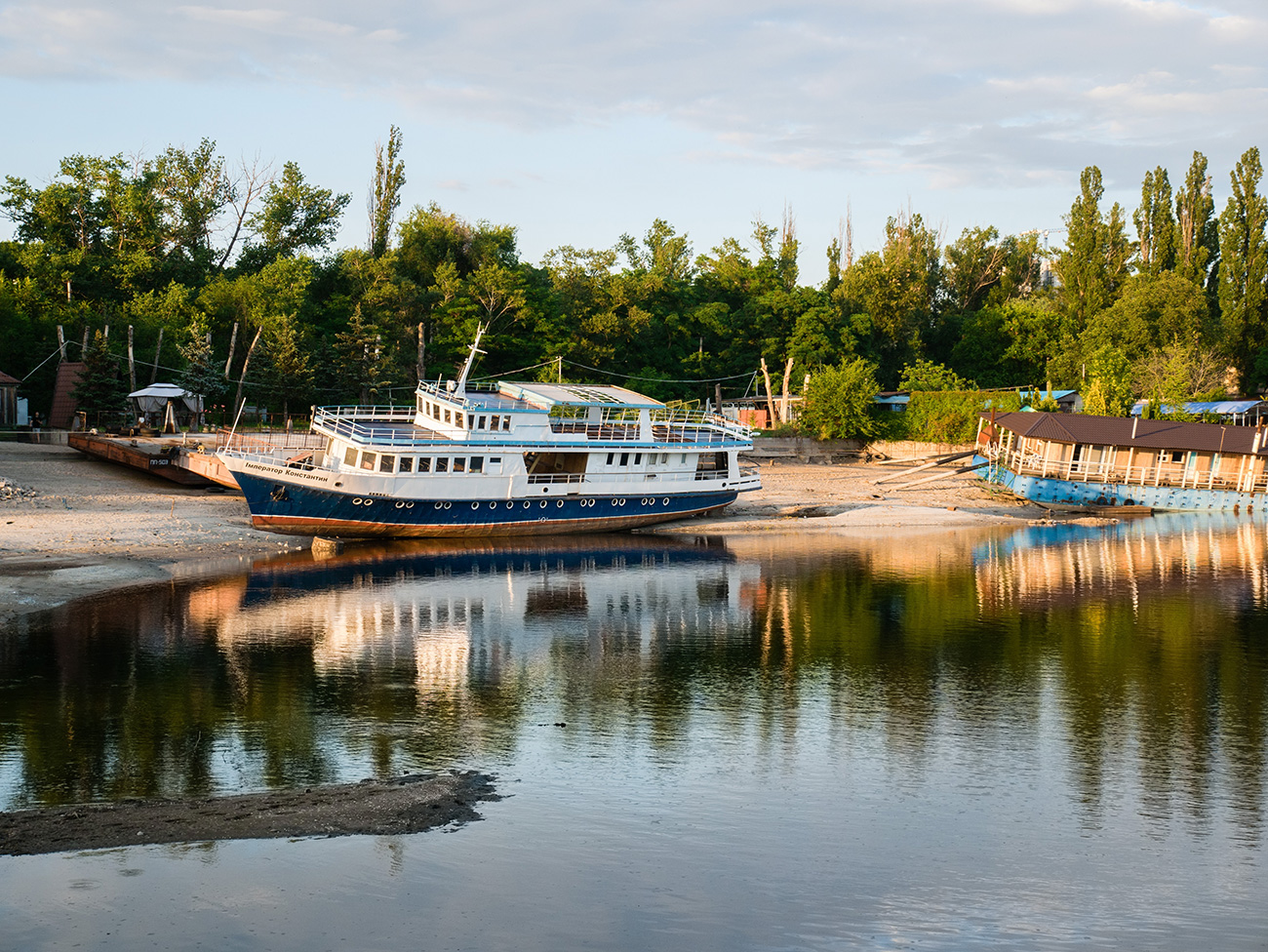 Zaporizhzhia, Ukraine - June 16, 2023: Shallowing of the Dnieper River due to the destruction of the Kakhovka dam and hydroelectric power station. River pleasure-excursion vessel is now on the shore.