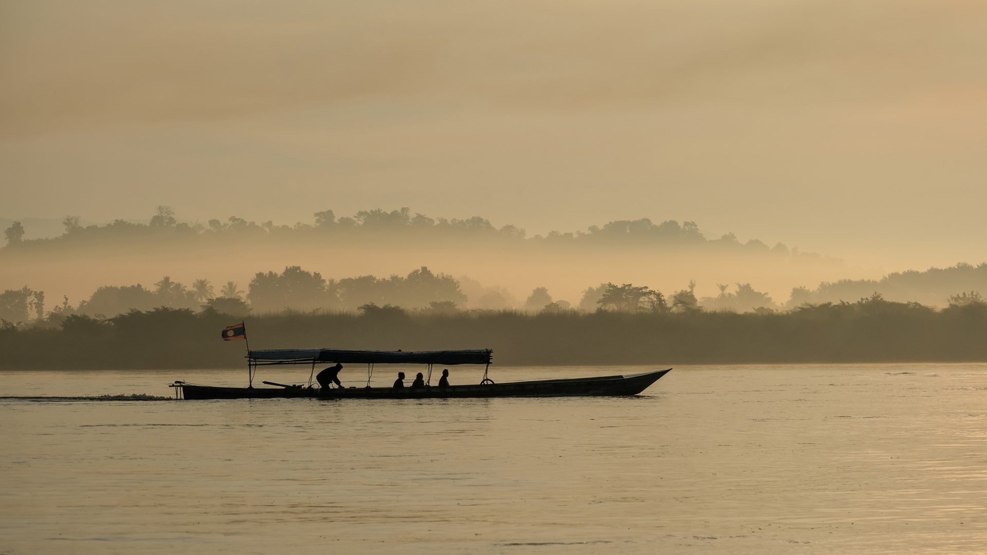Boat sailing along the Mekon River in a misty sunrise