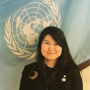 Woman smiling in front of a UN poster
