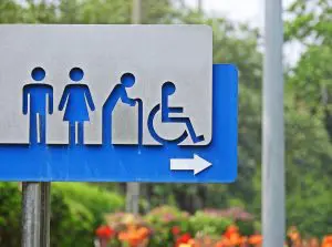 Blue and grey toilet sign with icons of a man, a woman, an elderly person and a person in wheelchair