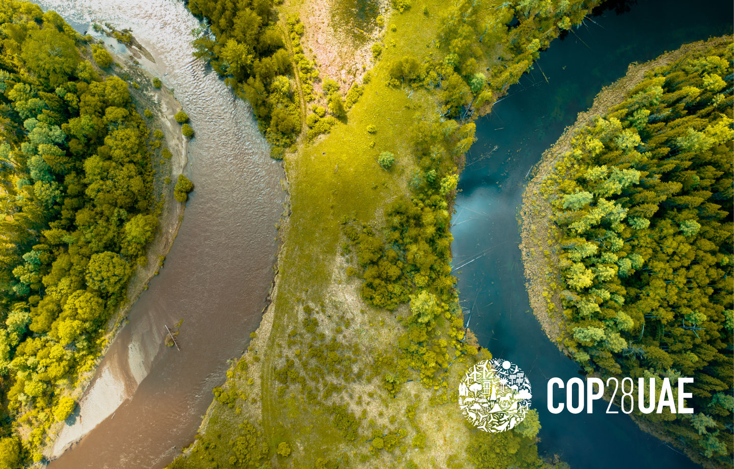 Aerial view of 2 rivers side by side in a green forest: a brown, dirty river on the left and a blue clean river on the right