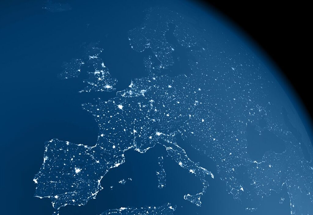 A realistic image of the earth from space at night with light emissions from large urban areas and atmospheric haze. The center of the view is Europe. The image is a rendered 3d scene.
