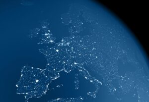 A realistic image of the earth from space at night with light emissions from large urban areas and atmospheric haze. The center of the view is Europe. The image is a rendered 3d scene.